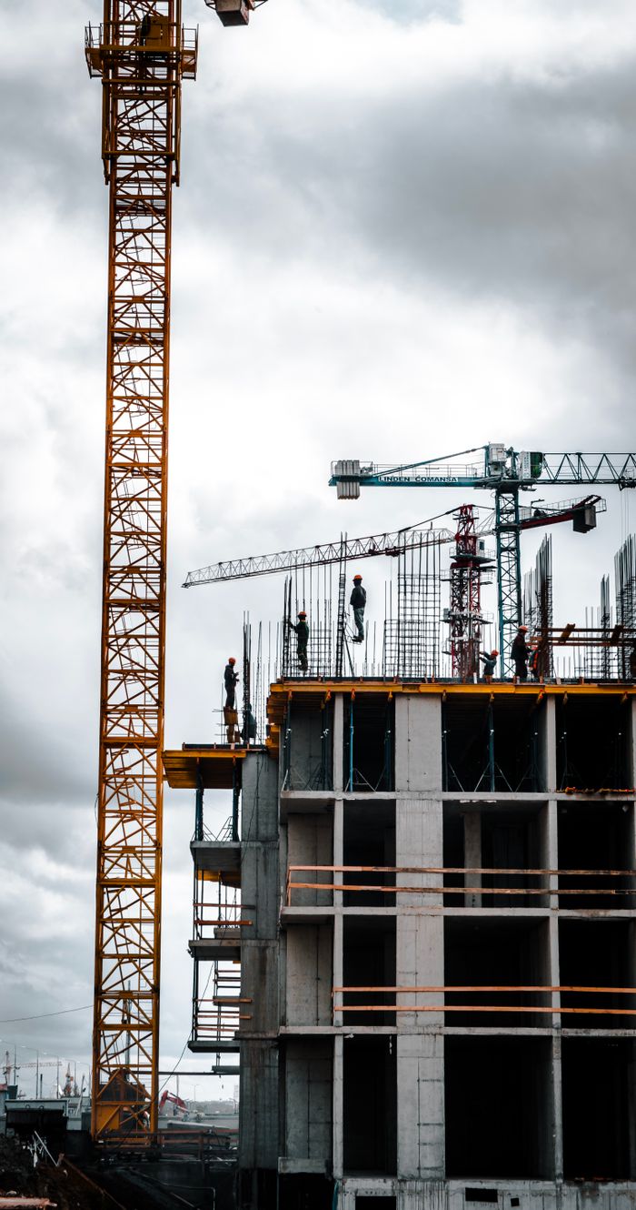 creative-03 Vertical view of a construction site with cranes and workers building a skyscraper.