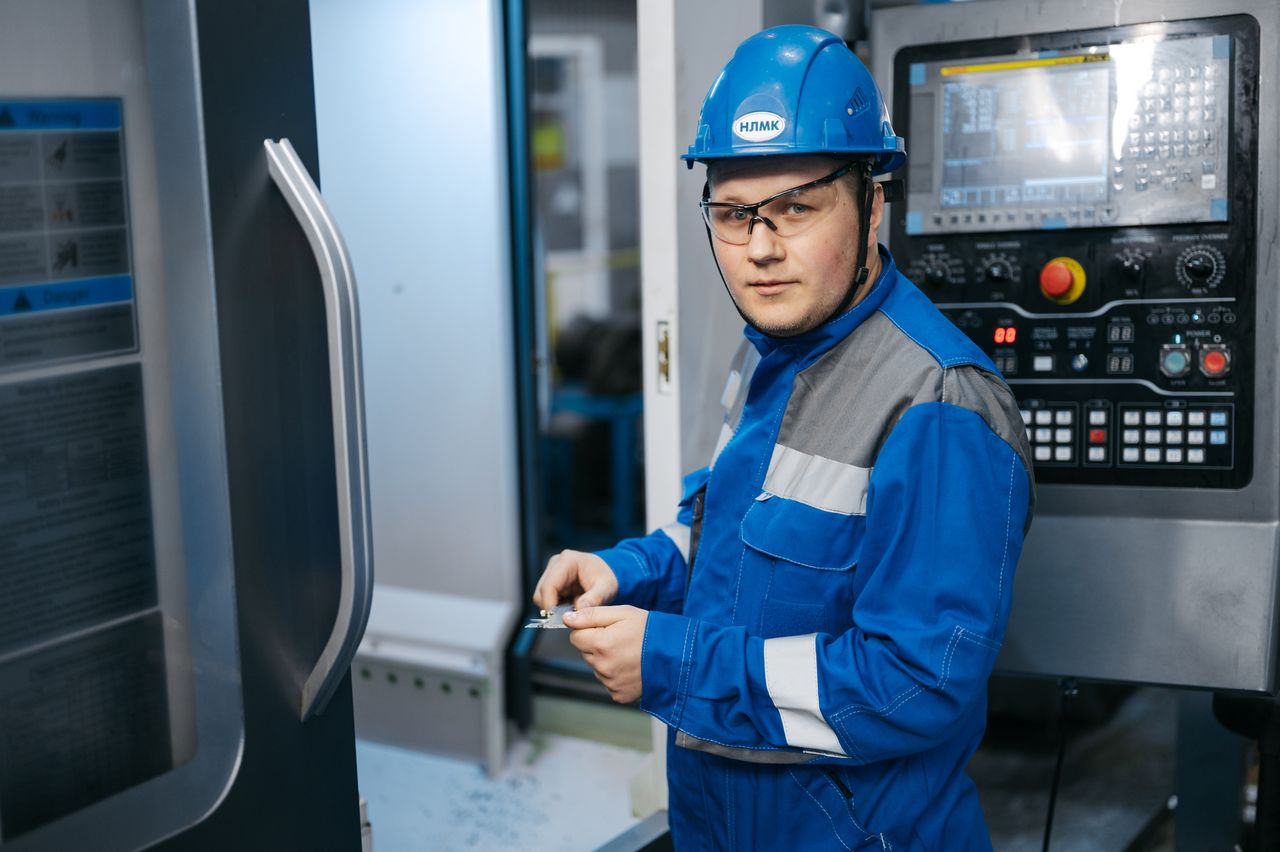 creative-01 Industrial engineer in safety gear working on a CNC machine in a modern factory setting.