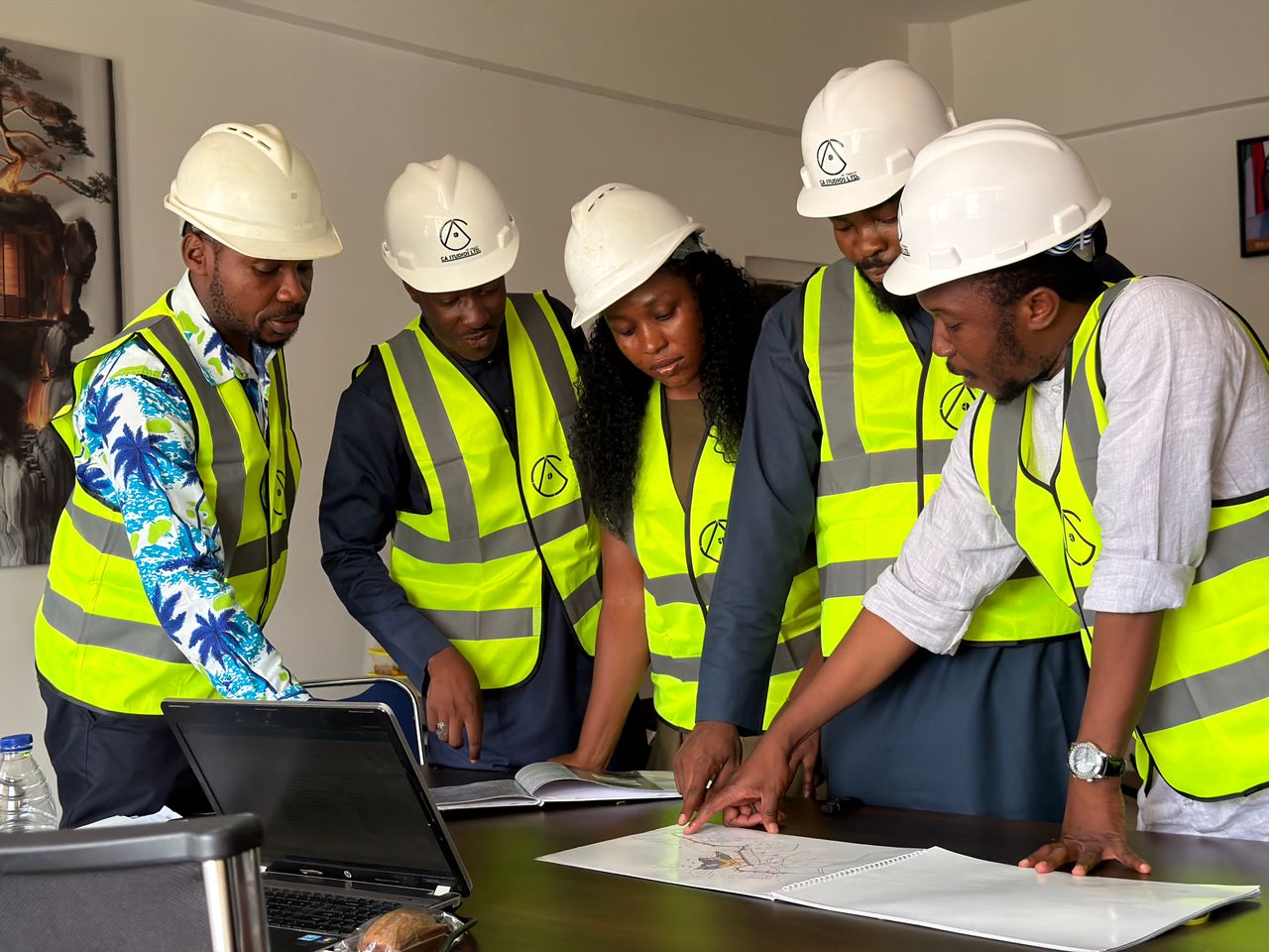 mobile-02 Group of engineers in safety gear reviewing blueprints indoors.