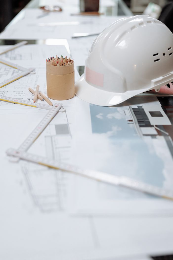 creative-02 A detailed view of an architect's desk with plans, a hard hat, and drafting tools.